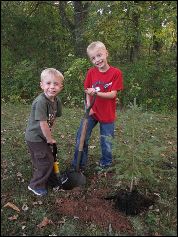 Photo: Two young boys, planting a tree.